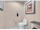 Neutral-toned powder room featuring a white toilet, white walls and a metal and glass side table at 125 E Harmon Ave # 2220, Las Vegas, NV 89109