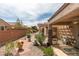View of the backyard with brick pathway, desert landscaping, and covered patio area with ceiling fan at 2105 High Mesa Dr, Henderson, NV 89012