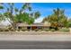 Wide front view of the single story home with lush trees and a low brick fence at 3015 Duneville St, Las Vegas, NV 89146