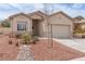 Single-story home with a two-car garage, desert landscaping, and neutral stucco exterior at 3239 Robins Creek Pl, Las Vegas, NV 89135