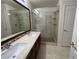 This bathroom features dual sinks, wood cabinets, and a glass-enclosed shower with tile surround at 5554 Chicory Falls Ct, Las Vegas, NV 89148
