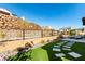 A backyard offers privacy with terraced retaining wall, artificial turf, and stone walkway at 59 Desert Ivy Ln, Henderson, NV 89011