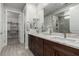 Modern bathroom with dual sinks, marble countertops, and view into tiled shower and walk in closet at 59 Desert Ivy Ln, Henderson, NV 89011