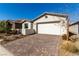 Attractive single-story home with a brick driveway, manicured landscaping, and an attached garage at 59 Desert Ivy Ln, Henderson, NV 89011