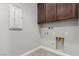 Practical laundry room with overhead cabinets, utility hook-ups, and tile flooring at 59 Desert Ivy Ln, Henderson, NV 89011