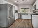 Updated kitchen featuring stainless steel appliances, white cabinets, and a large farmhouse sink with natural light at 6520 Ouida Way, Las Vegas, NV 89108