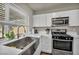 Stylish kitchen with stainless steel appliances, white cabinets, quartz countertop and a stainless steel farmhouse sink at 6520 Ouida Way, Las Vegas, NV 89108
