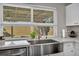 Close-up of a modern kitchen sink with quartz countertop, stylish faucet, and a view to the outdoors at 6520 Ouida Way, Las Vegas, NV 89108