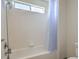 Bright bathroom featuring white tiling, a shower-tub combination with updated fixtures, and a clean, modern design at 6971 Cedar Basin Ave, Las Vegas, NV 89142