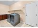 Spacious laundry room with front-load washer and dryer, storage shelf, and tiled floor at 6982 Mirkwood Ave, Las Vegas, NV 89178
