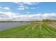 A picturesque view of a scenic pond with grassy shore under a partly cloudy sky at 757 Omaggio Pl, Henderson, NV 89011