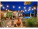 Inviting backyard with stone patio, desert landscaping, and a sparkling pool, illuminated by overhead string lights at 8113 Bay Colony St, Las Vegas, NV 89131