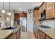 Open concept kitchen with a stainless steel refrigerator, granite counters, wood cabinets, and gas cooktop at 8113 Bay Colony St, Las Vegas, NV 89131