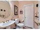 Elegant powder room featuring a pedestal sink, decorative mirror, and neutral color palette at 8698 Waterford Bend St, Las Vegas, NV 89123