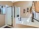 Bathroom showcasing a white jetted tub, glass shower enclosure, and neutral color palette at 8698 Waterford Bend St, Las Vegas, NV 89123