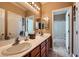 Bathroom featuring double sinks, a large mirror, and an open doorway to the shower and bathtub at 8698 Waterford Bend St, Las Vegas, NV 89123