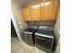 Modern laundry room with stainless steel washer and dryer, and overhead storage cabinets at 8698 Waterford Bend St, Las Vegas, NV 89123