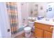 Bathroom with wood cabinets, tiled floor, shower-tub with colorful curtain, toilet and sink at 928 Collingtree St, Las Vegas, NV 89145