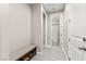 Hallway with a bench and a view into the bathroom with light wood-look tile floor and neutral colored walls at 10101 Heron Lake Ave, Las Vegas, NV 89178