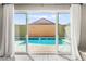 View of a private pool from inside the house through sliding glass doors with white curtains at 10101 Heron Lake Ave, Las Vegas, NV 89178