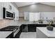 Modern kitchen with black and white cabinets, granite countertops, a gas range and stainless steel appliances at 1110 Azure Heights Pl, Las Vegas, NV 89110