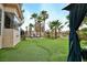 Well-manicured backyard with artificial grass, palm trees, lounge chairs, and a covered gazebo at 129 Chateau Whistler Ct, Las Vegas, NV 89148