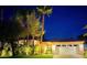 Beautiful single-story home with lush landscaping and a two-car garage, warmly lit against a night sky at 129 Chateau Whistler Ct, Las Vegas, NV 89148