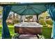 Relaxing backyard hot tub with gazebo featuring draped curtains, towels and green plants at 129 Chateau Whistler Ct, Las Vegas, NV 89148