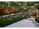 Expansive backyard featuring a manicured lawn, elegant landscaping, and a charming stone patio with ambient lighting at 1309 Reisling Ct, Las Vegas, NV 89144