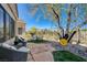 Relaxing backyard with stone patio, comfortable seating, and a mature tree for shade at 1372 Couperin Dr, Henderson, NV 89052