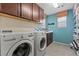 Well-organized laundry room with washer, dryer, cabinets, and a storage shelf at 1776 Gentle Brook St, North Las Vegas, NV 89084