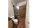 Bathroom features a glass-enclosed shower with brown tile and a toilet next to a wooden cabinet at 1830 N Buffalo Dr # 2098, Las Vegas, NV 89128
