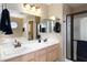 Bright bathroom featuring double vanity, a large mirror and an enclosed shower with black hardware at 2219 Rugged Mesa Dr, Laughlin, NV 89029