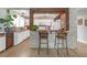 Eat in kitchen featuring a bar top, white cabinetry, and laminate wood flooring at 4394 El Campana Way, Las Vegas, NV 89121