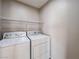 A well-lit laundry room features a washing machine, dryer, and overhead shelving at 5664 Dawn Falls St, Las Vegas, NV 89148