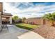 Spacious backyard featuring a covered patio, grass, mature trees, and colorful chairs at 7386 Campbell Ranch Ave, Las Vegas, NV 89179
