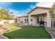 Backyard with an artificial putting green, grass area, and covered patio with seating at 7386 Campbell Ranch Ave, Las Vegas, NV 89179