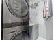 Modern laundry area with stacked washer and dryer, storage cabinet, and hanging clothes at 7386 Campbell Ranch Ave, Las Vegas, NV 89179