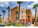 Exterior view of a multi-story condominium building with desert landscaping and tall palm trees at 75 E Agate Ave # 204, Las Vegas, NV 89123