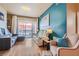 Open living room with light wood floors, a comfortable gray sofa, and access to a private balcony at 75 E Agate Ave # 204, Las Vegas, NV 89123