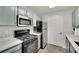 Modern kitchen featuring stainless steel appliances, a gas range, sleek countertops, and green cabinets at 950 Seven Hills Dr # 124, Henderson, NV 89052