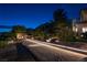A beautiful backyard with a boules court, an outdoor fireplace, and stone retaining walls illuminated at twilight at 9533 Orient Express Ct, Las Vegas, NV 89145
