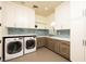 Well-organized laundry room with modern washer and dryer, attractive blue backsplash, and ample storage in sleek white cabinets at 9533 Orient Express Ct, Las Vegas, NV 89145