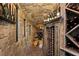 Rustic wine cellar with stone walls, custom wine racks, and ambient lighting for the wine enthusiast at 9533 Orient Express Ct, Las Vegas, NV 89145