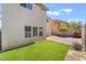 Backyard featuring a patch of artificial grass, brick patio, and desert landscaping at 9785 Iron Mine St, Las Vegas, NV 89183