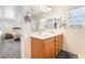 Bright bathroom with dual sinks, wood cabinets, large mirror, and access to the bedroom at 9785 Iron Mine St, Las Vegas, NV 89183