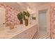 Stylish bathroom with pink wallpaper, double sinks, and unique floor tiles at 9992 Sky Parlor Rd, Las Vegas, NV 89178