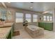 Bright bathroom features soaking tub, walk in shower, and double sinks with green cabinets at 9992 Sky Parlor Rd, Las Vegas, NV 89178