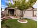 Inviting single-story home with lush, green lawn, mature shade tree, and a two-car garage at 1100 Warm Canyon Way, Las Vegas, NV 89123