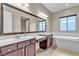 Bathroom featuring dual vanities, soaking tub, framed mirror, and wood cabinets at 11274 Felice Cohn Ct, Las Vegas, NV 89179